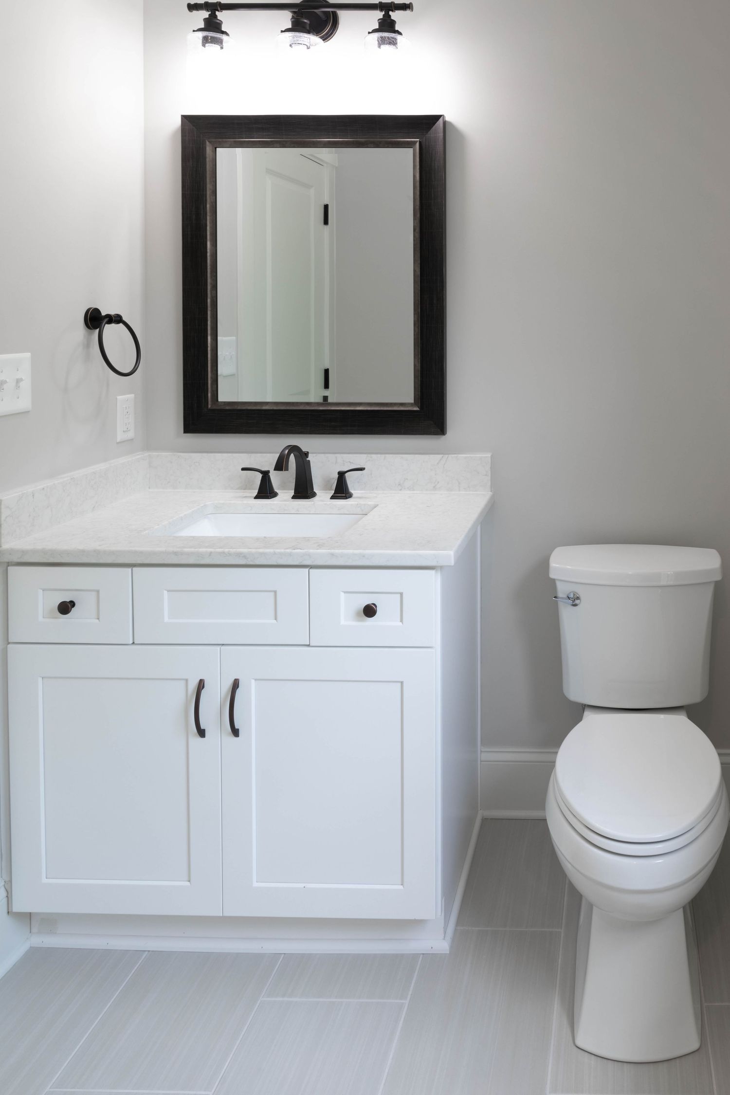Clean modern bathroom with white vanity, framed mirror, and black fixtures.