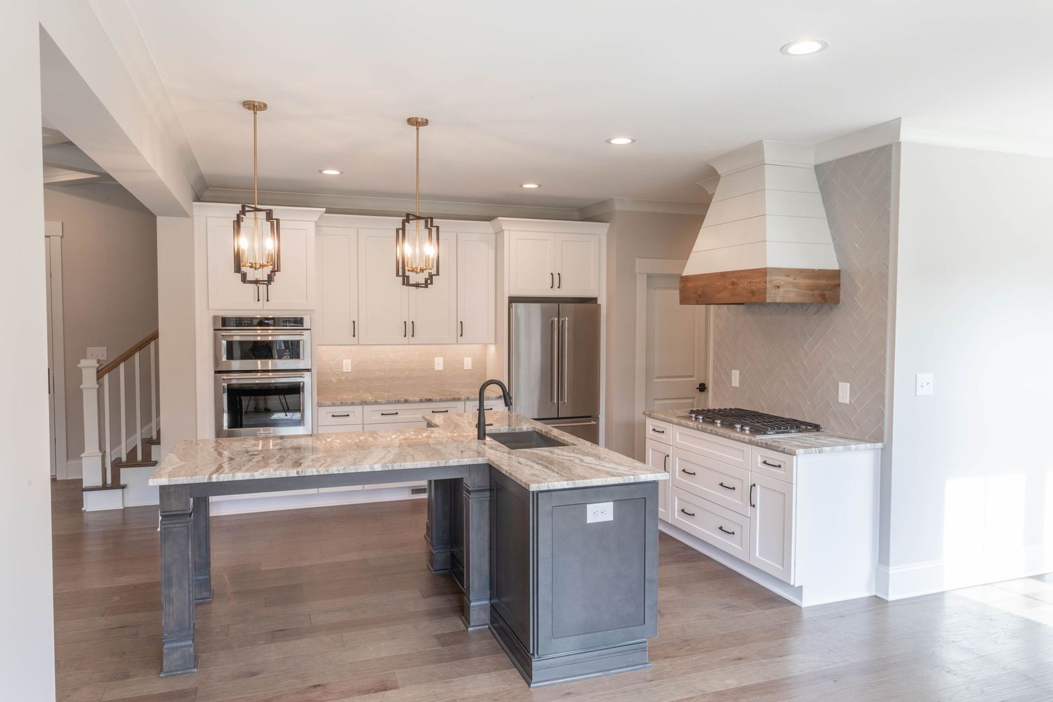 Modern kitchen with white cabinets, gray island, and pendant lighting featuring stainless steel appliances.