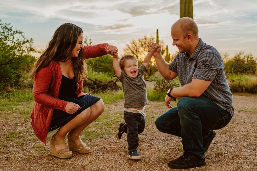 Family enjoying a sunset photoshoot among desert cacti and natural terrain.