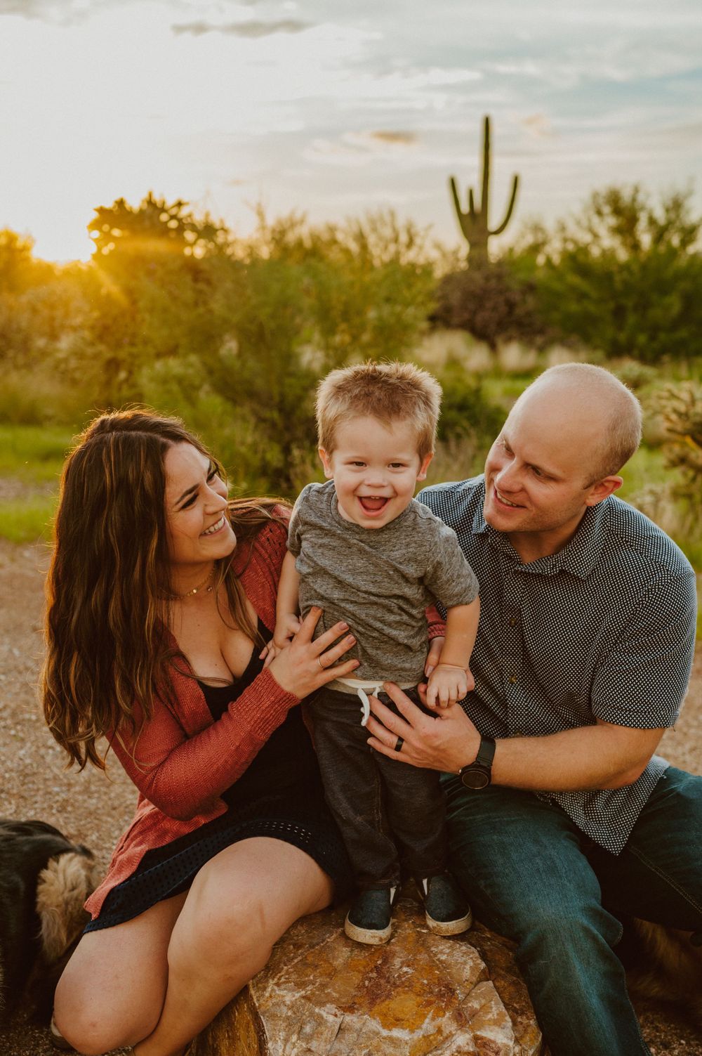 A candid family moment of laughter and joy in a desert setting during golden hour.