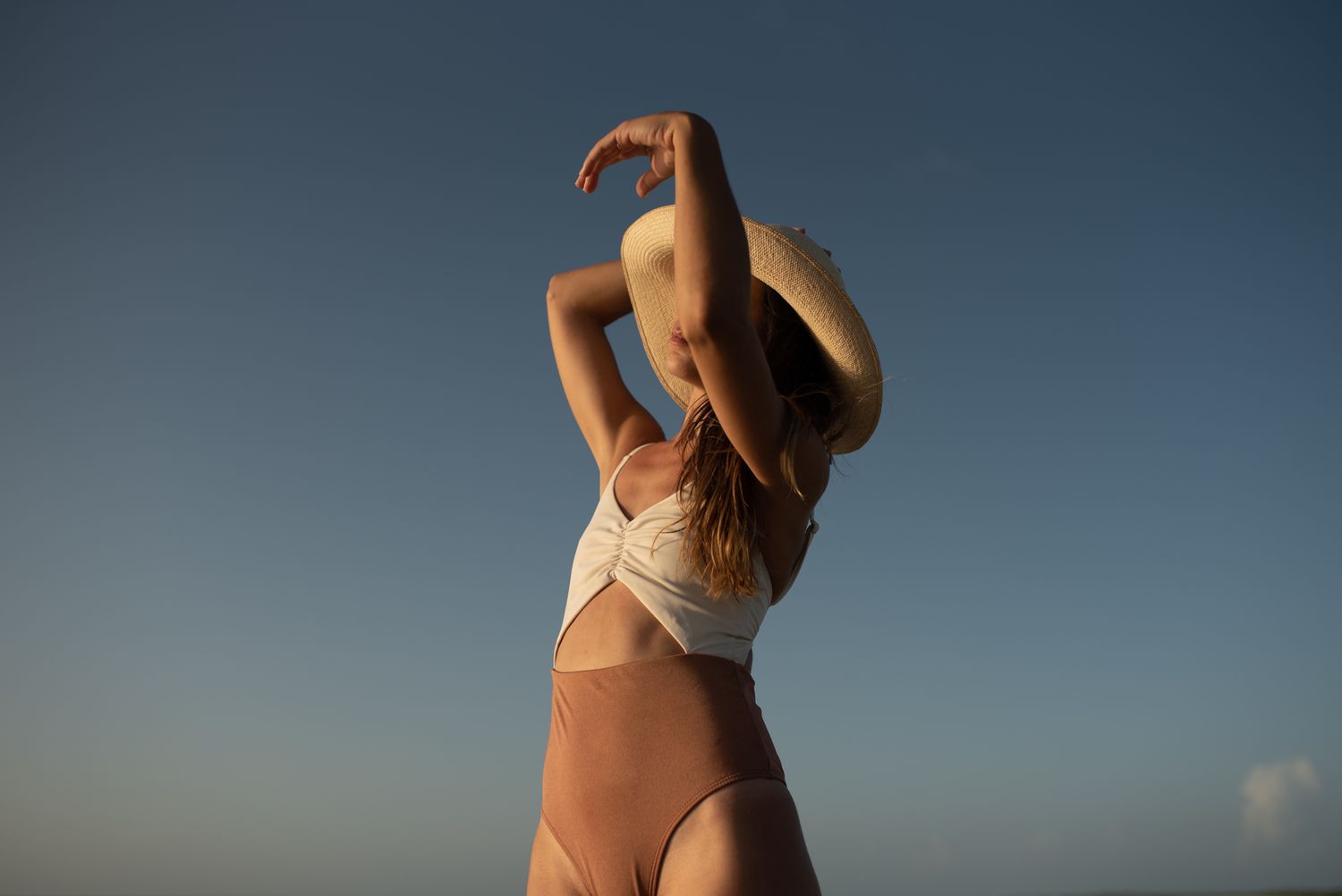 Silhouettes of a person in swimwear against a deep blue sky during golden hour.