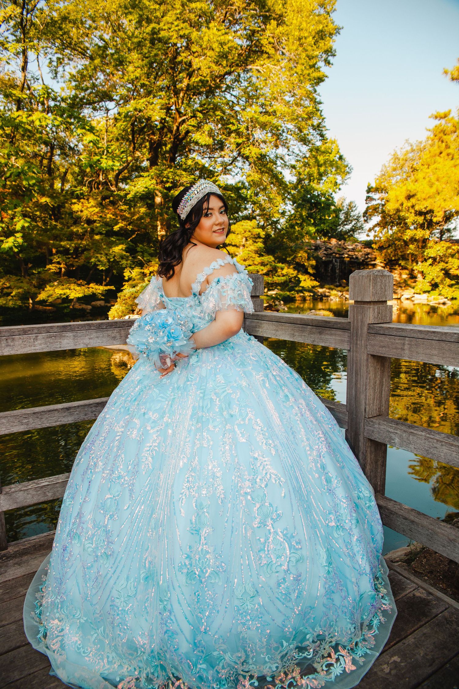 Light blue princess ballgown photographed on wooden bridge during golden autumn sunset.
