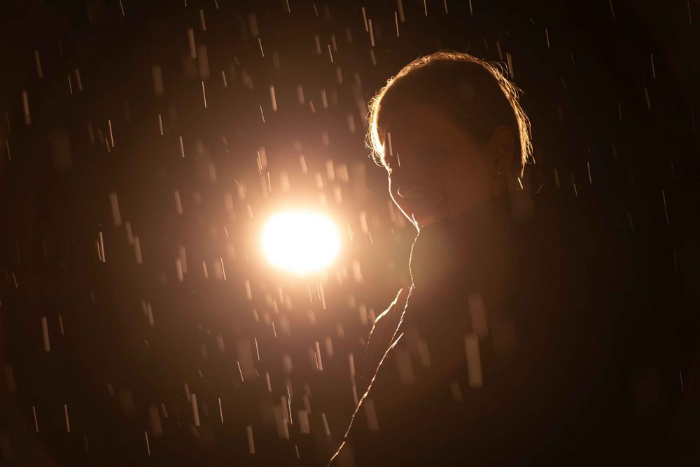 Silhouette against bright light with falling snow creating dramatic backlit effect.