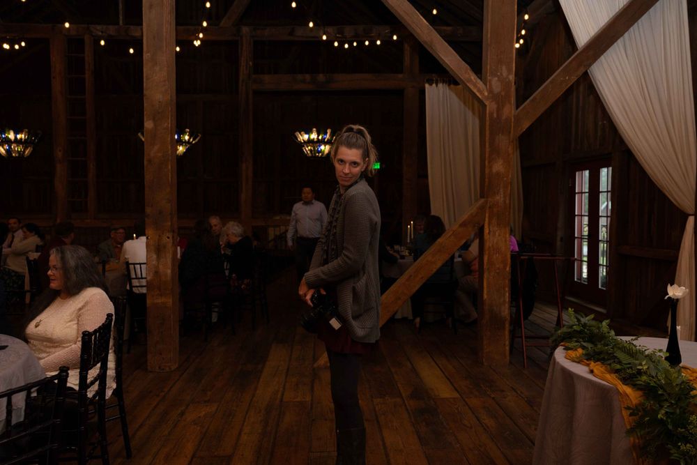 Event photographer working in rustic wooden venue with ambient lighting.