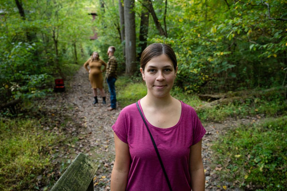 People walking on wooded trail during outdoor photo session.