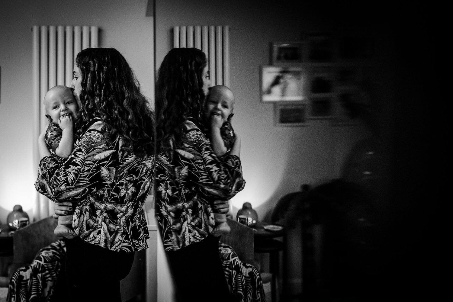 black and white photo of Mother cradling her one-year-old with a reflection in the television