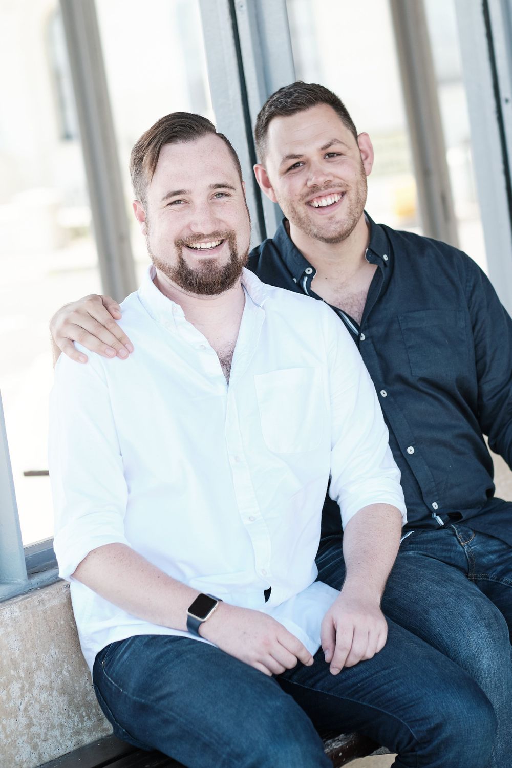 Happy couple in contrasting shirts sharing a warm embrace and genuine smiles.