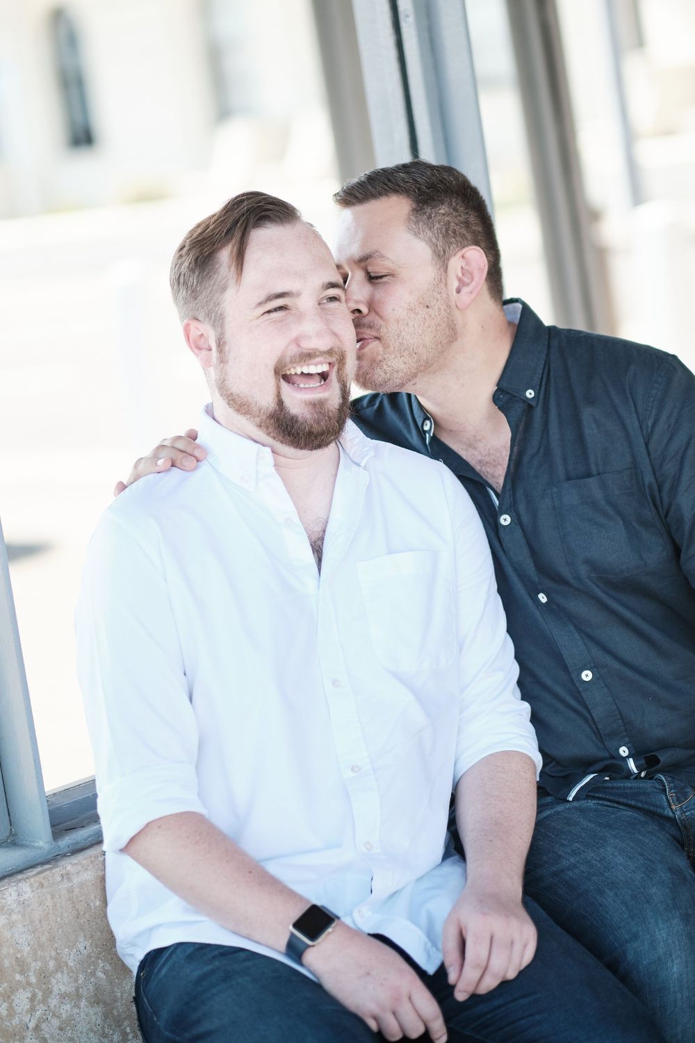 Intimate moment captured between two people sharing affection while sitting outdoors.