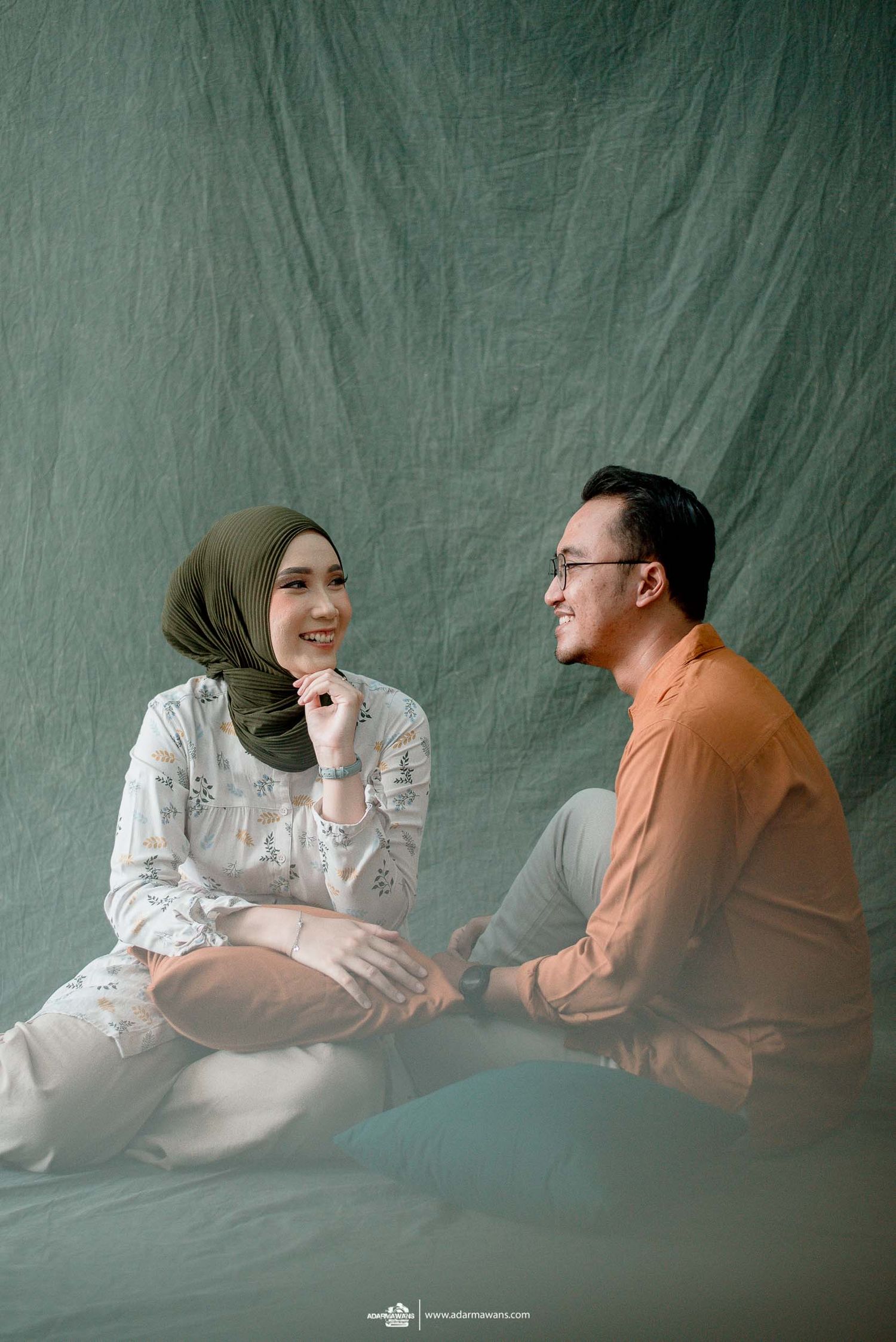 A couple sharing a lighthearted moment while sitting on the floor during their photoshoot.
