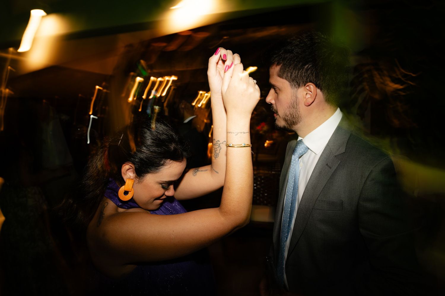 Wedding guests dancing under atmospheric lighting at evening reception.