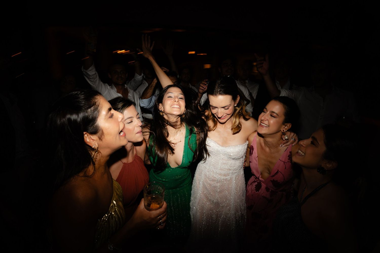 Party-goers dancing together in a dimly lit venue with dramatic spotlight effects.