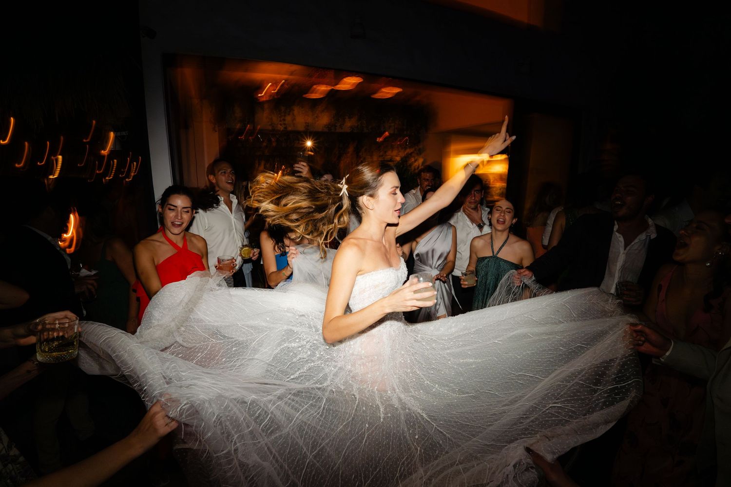 Wedding reception dance floor with bride in white dress surrounded by celebrating guests.