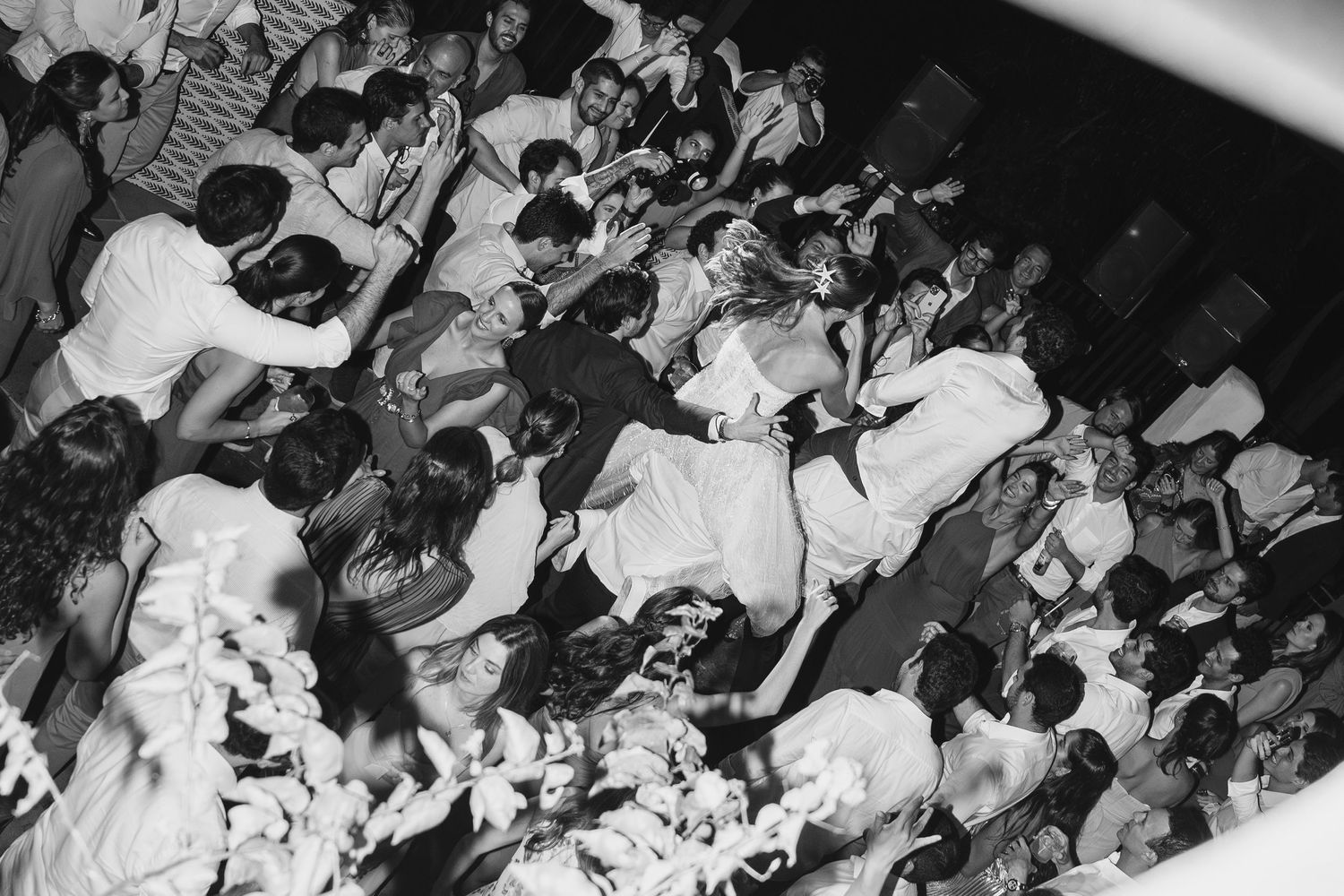Black and white photo of a crowded dance floor with people dancing in a chaotic energetic scene.