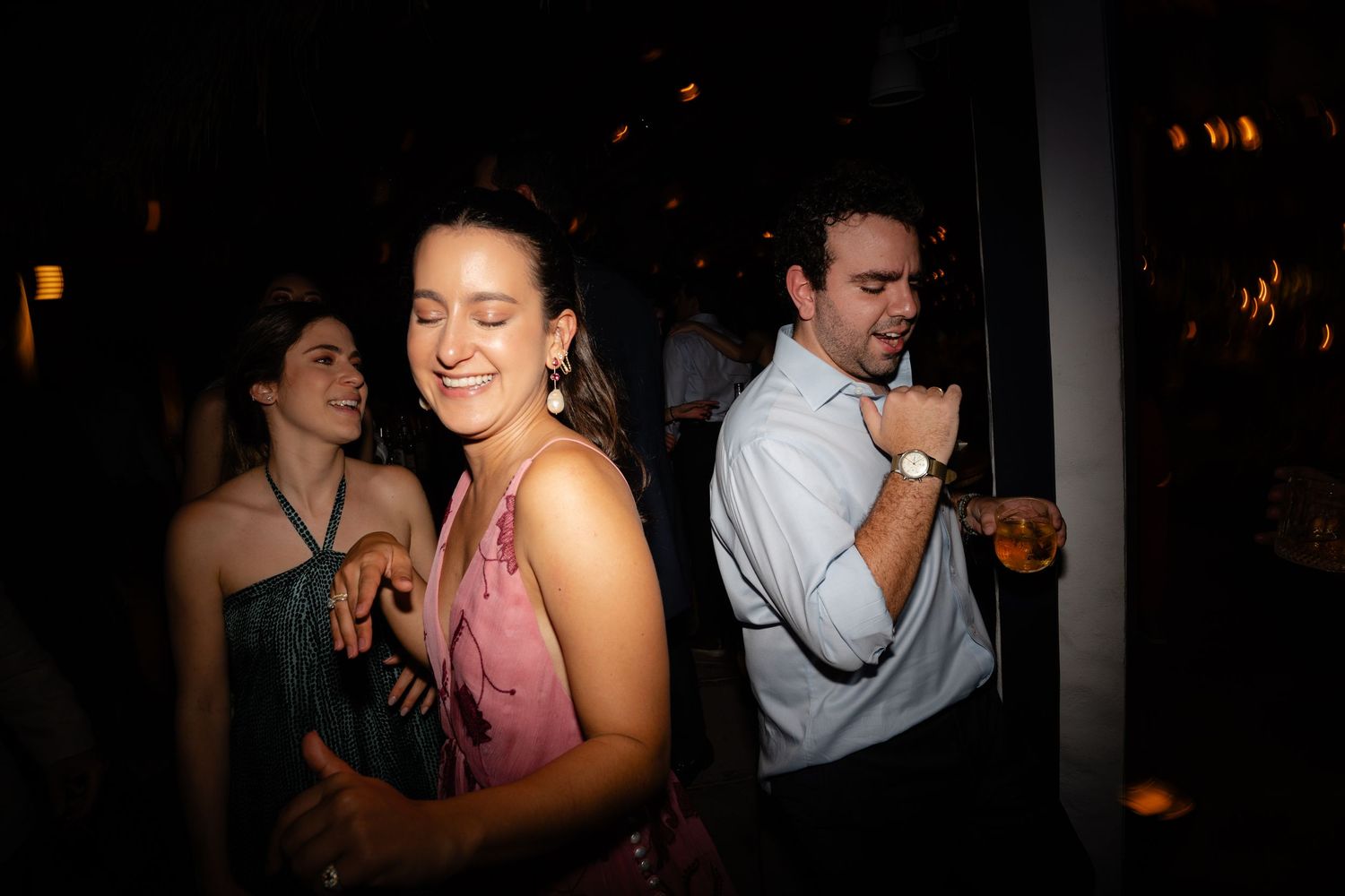 People dancing and enjoying themselves at a dimly lit nightclub party.