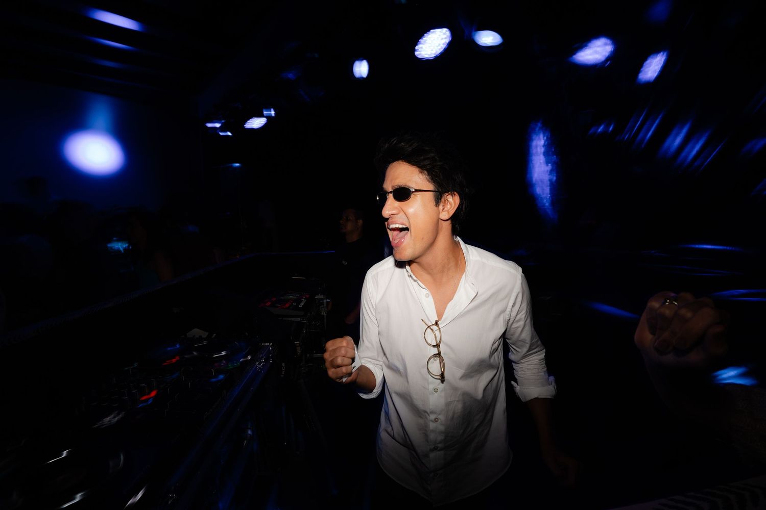 A person dancing enthusiastically under blue nightclub lights.