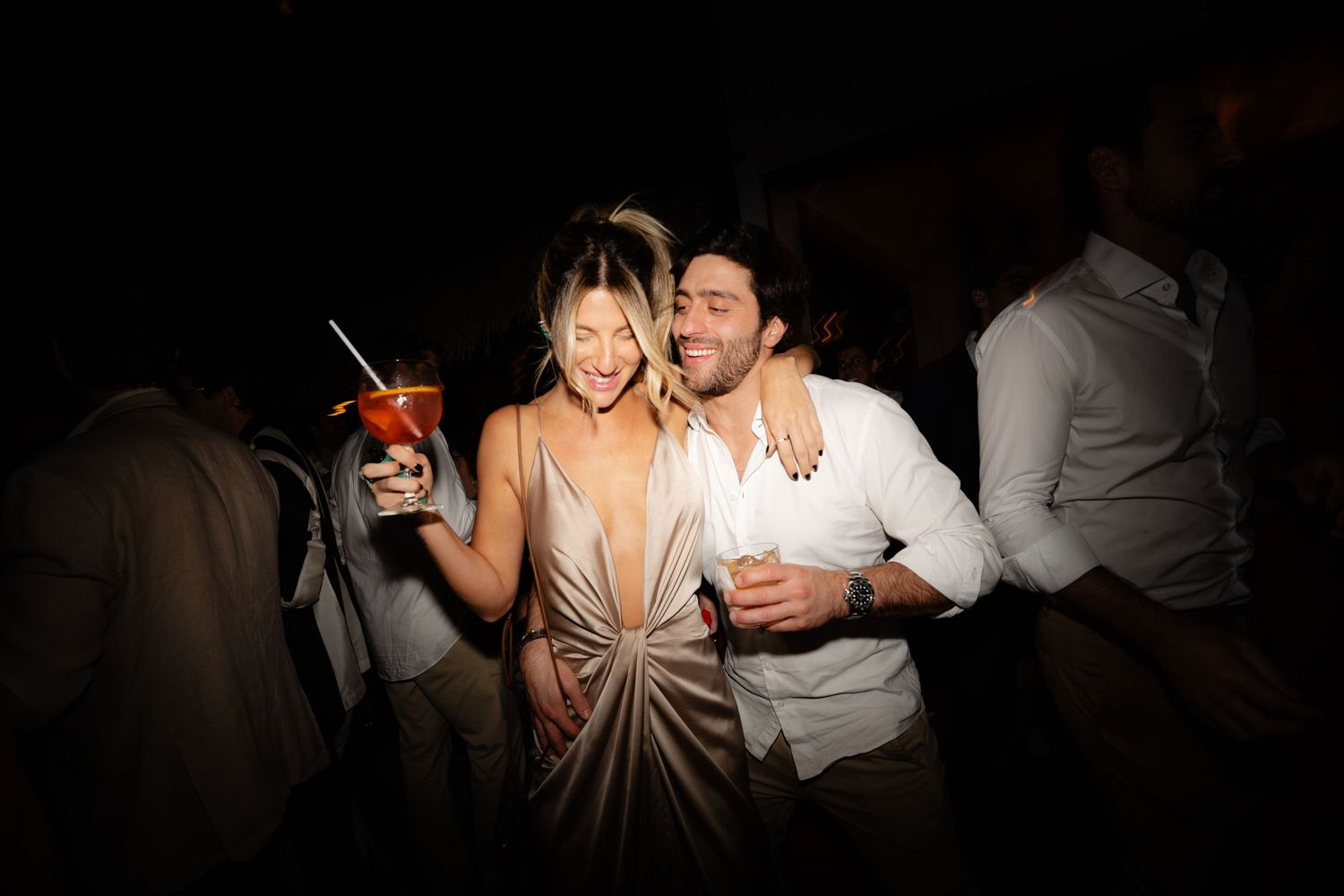 Couple enjoying drinks and dancing at a nighttime celebration.