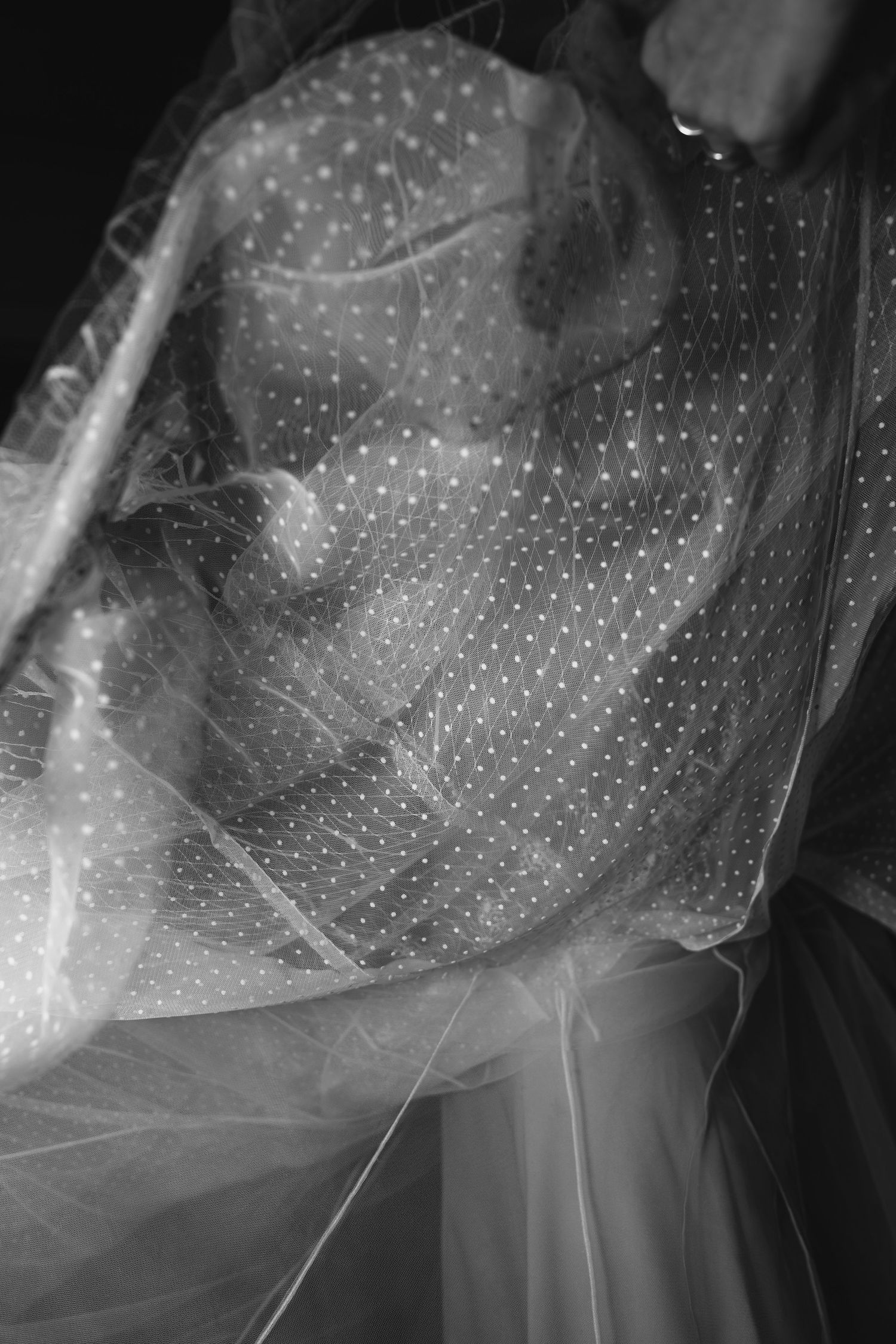 Close-up black and white detail of a polka dot wedding dress veil.