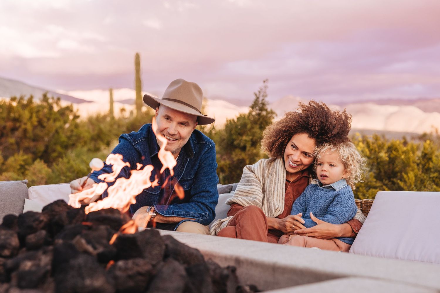 Family sharing a tender outdoor moment together under a large oak tree at sunset.