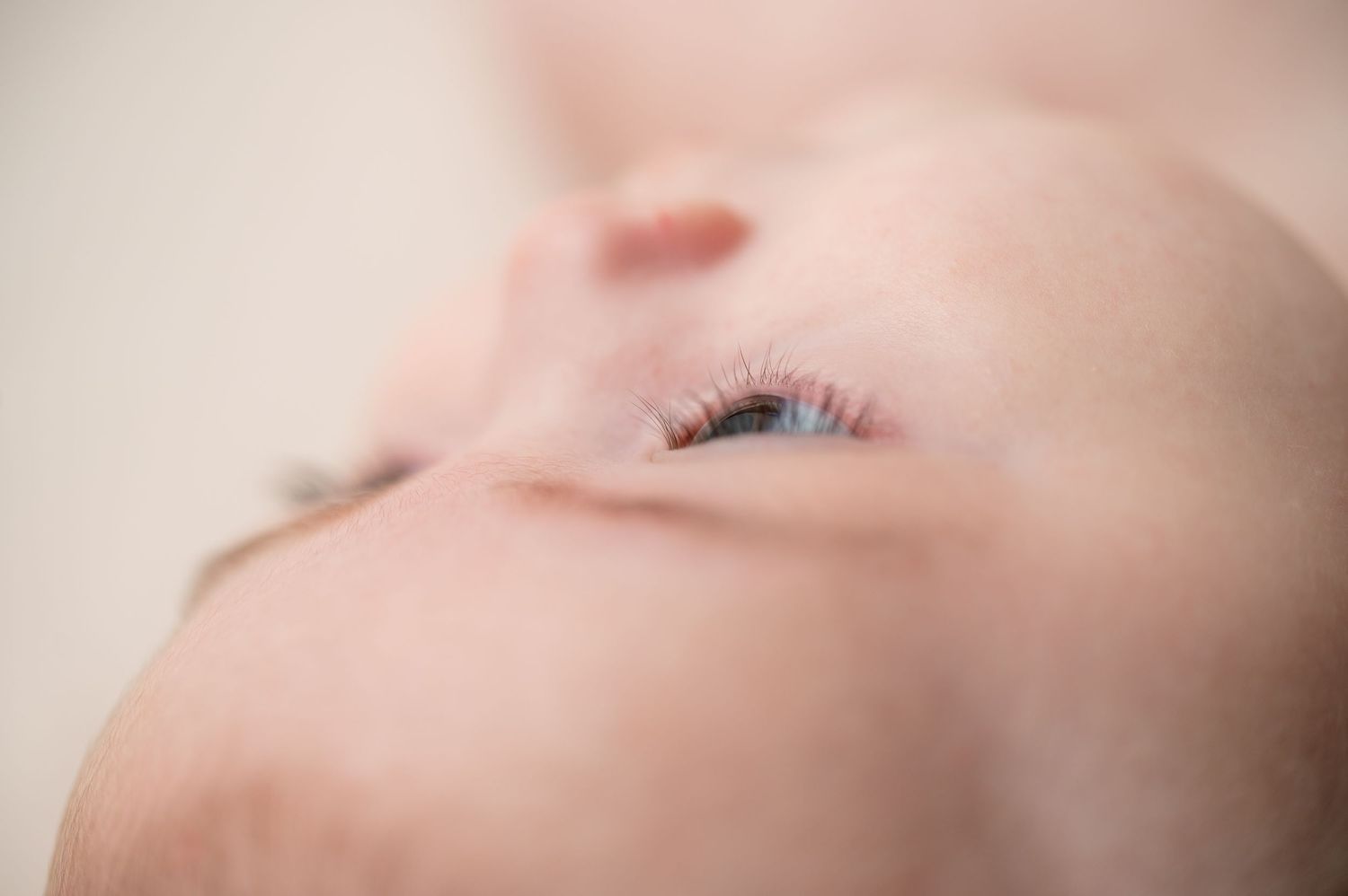 Dreamy close-up portrait of a baby's eye and cheek with soft lighting.