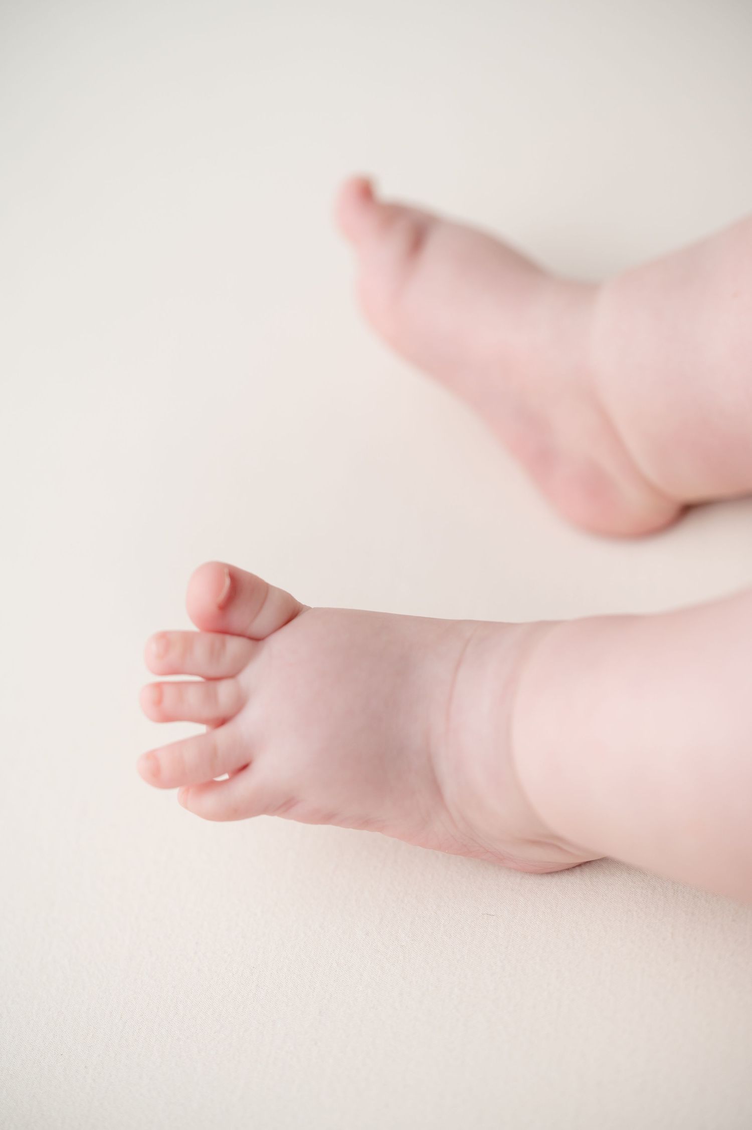 Close-up of tiny baby feet against a light background showing delicate toes and soft skin.