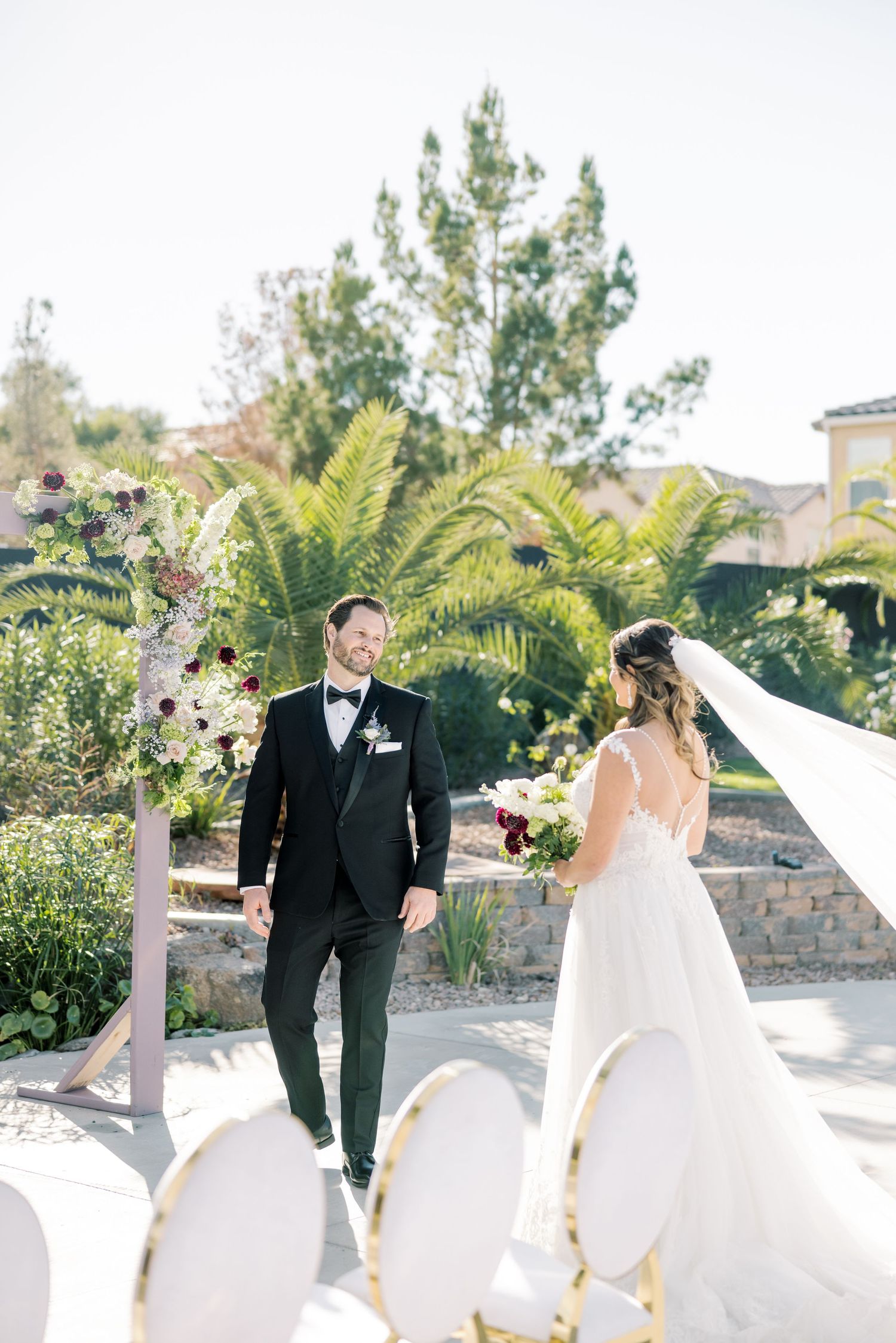 An outdoor wedding ceremony setup with white chairs and tropical palm trees.