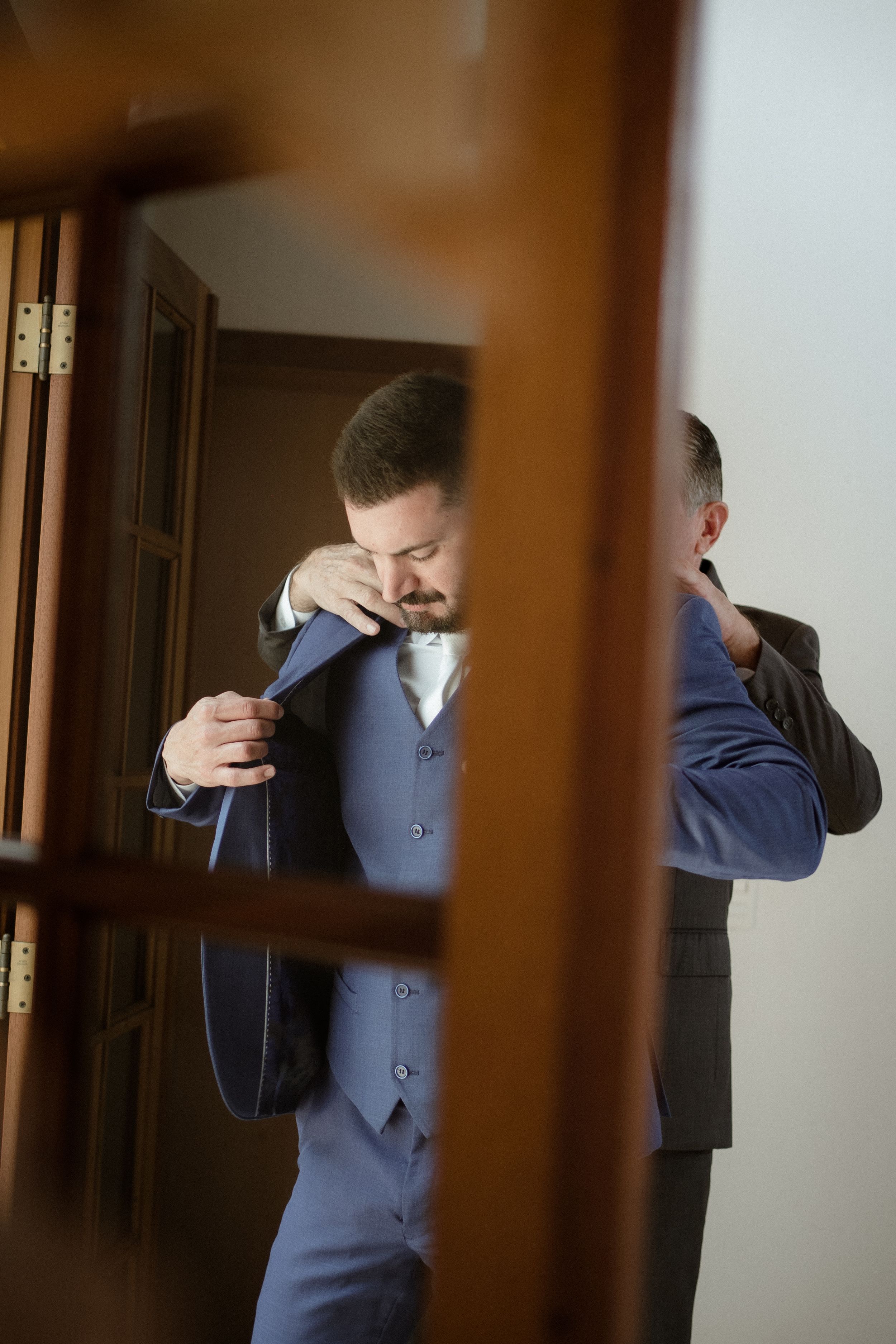 Artistic mirror reflection of someone adjusting formal attire in blue suit.