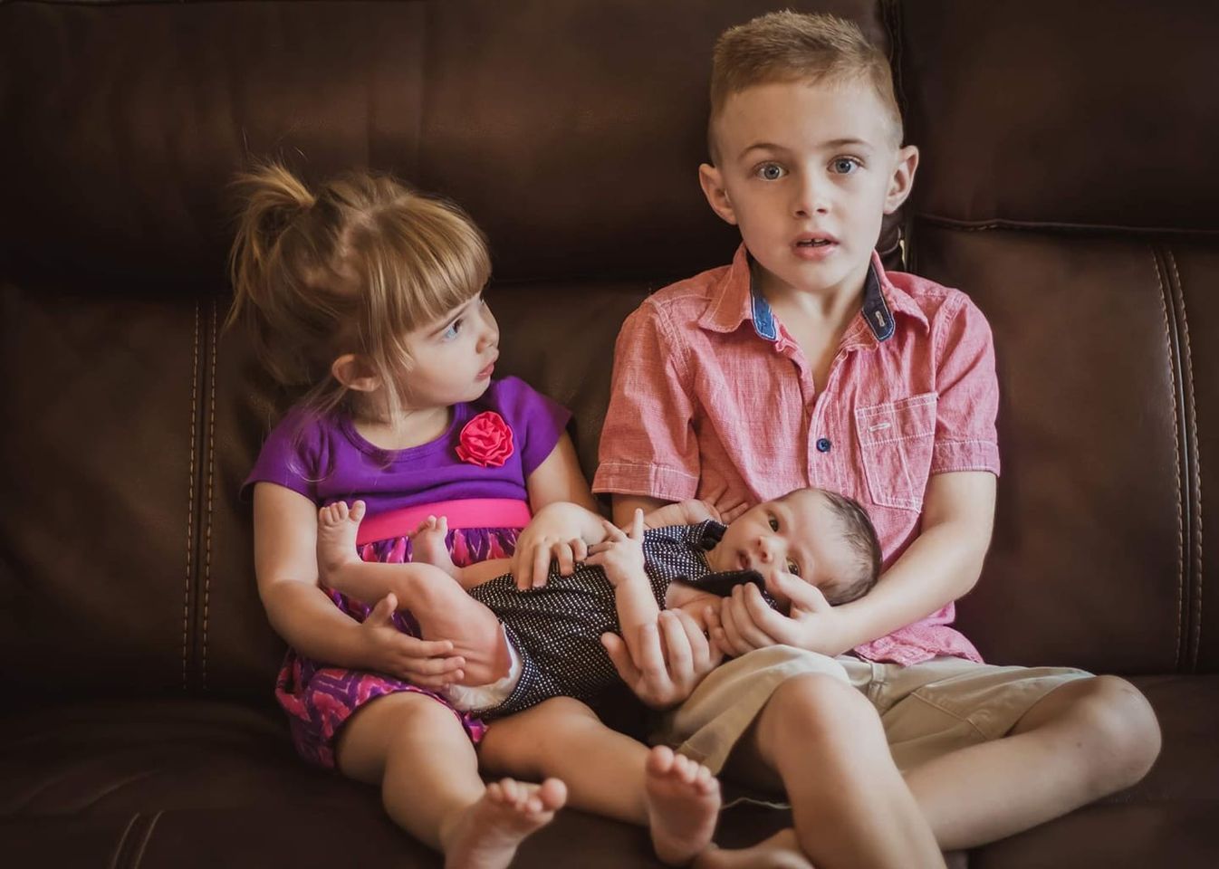 Siblings hold the new baby.