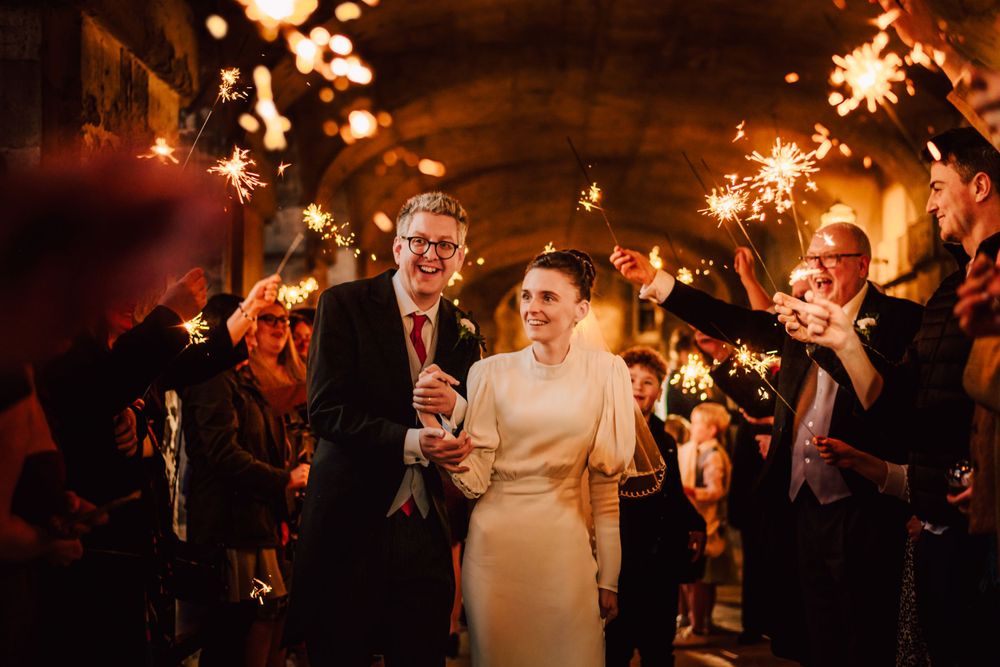 Wedding guests celebrate with sparklers at an outdoor evening reception creating magical light trails.