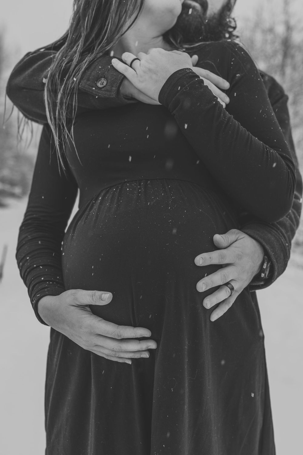 Black and white maternity photo showing embracing couple in winter.