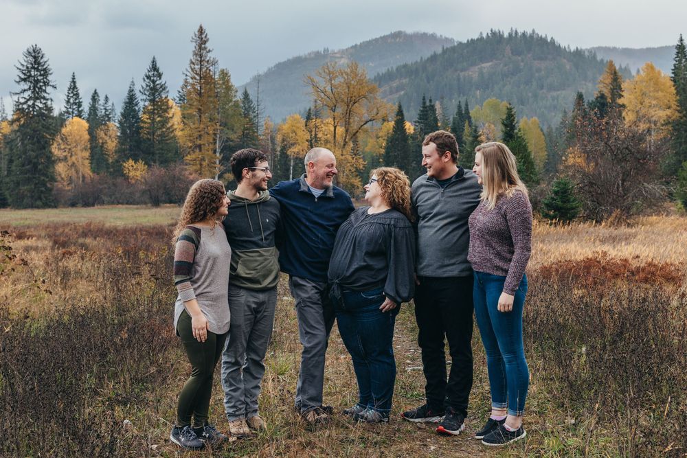 Family group photo with mountains and autumn trees in background.