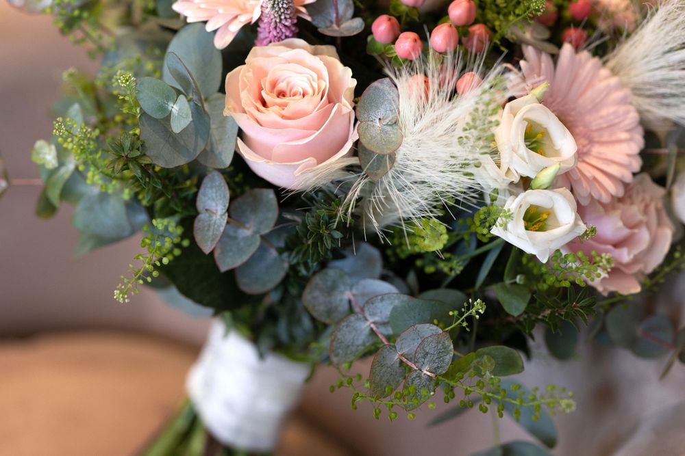 A delicate wedding bouquet featuring pink roses, eucalyptus, and white flowers with soft textures.