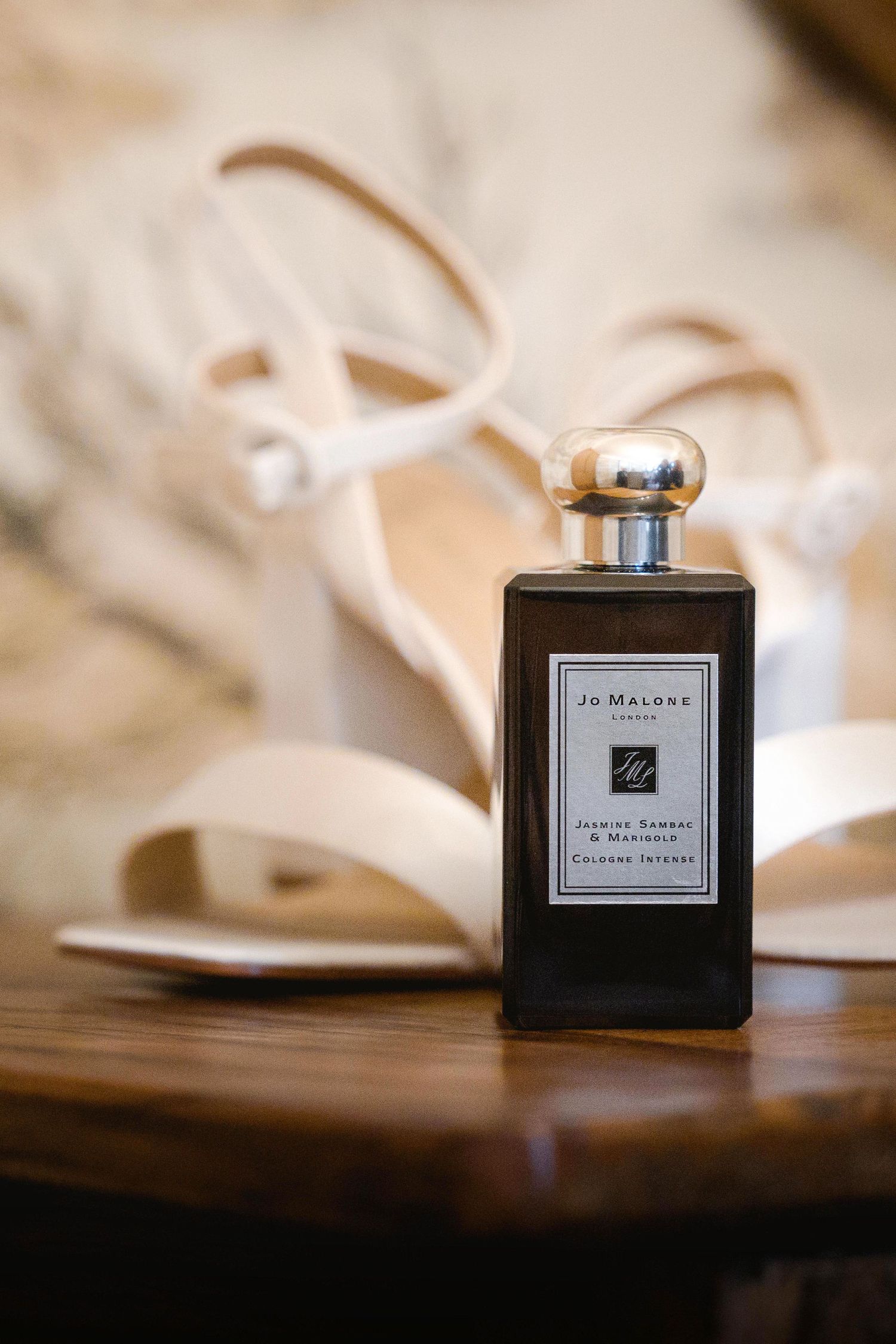 A Jo Malone perfume bottle elegantly positioned next to cream-colored wedding shoes.