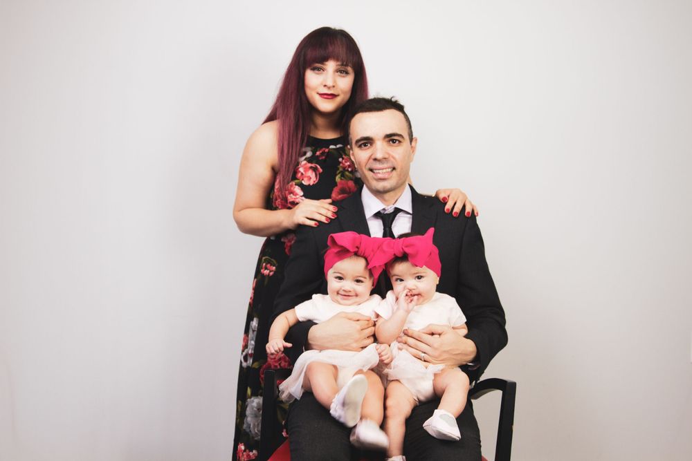 Studio portrait of a couple in formal wear holding twin babies in matching outfits.
