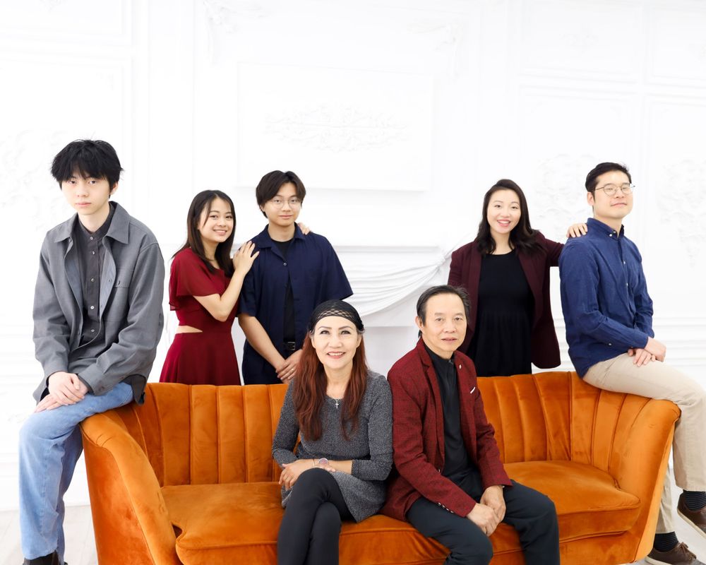 Group portrait of people seated and standing around an orange velvet couch in casual business attire.