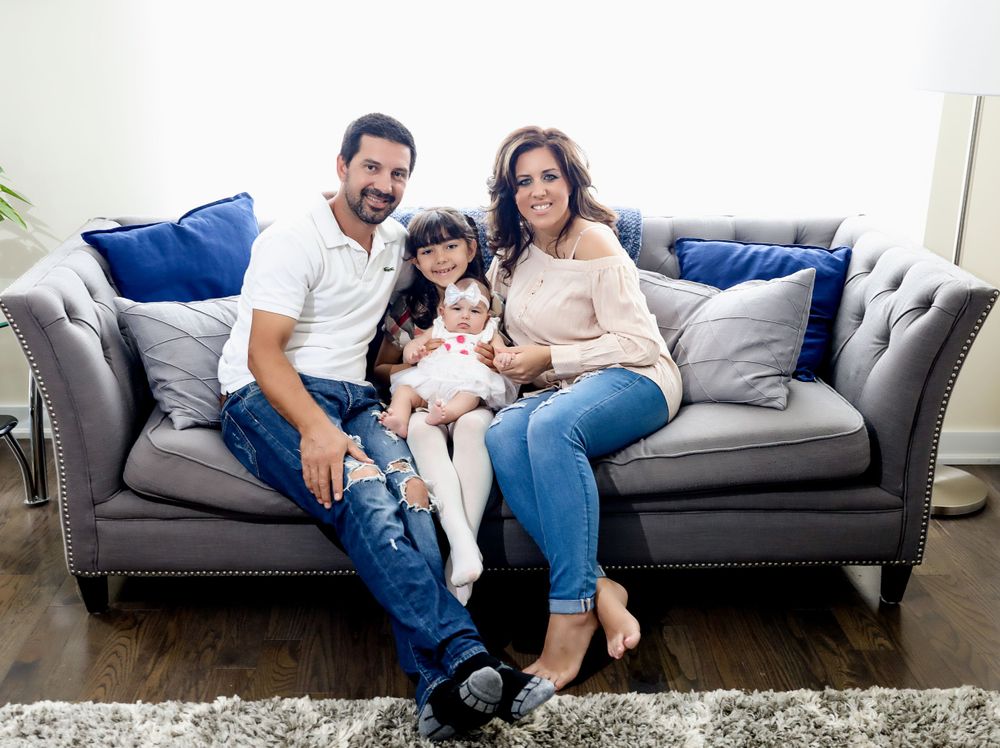 Family relaxing together on a plush gray couch in a modern living room setting.
