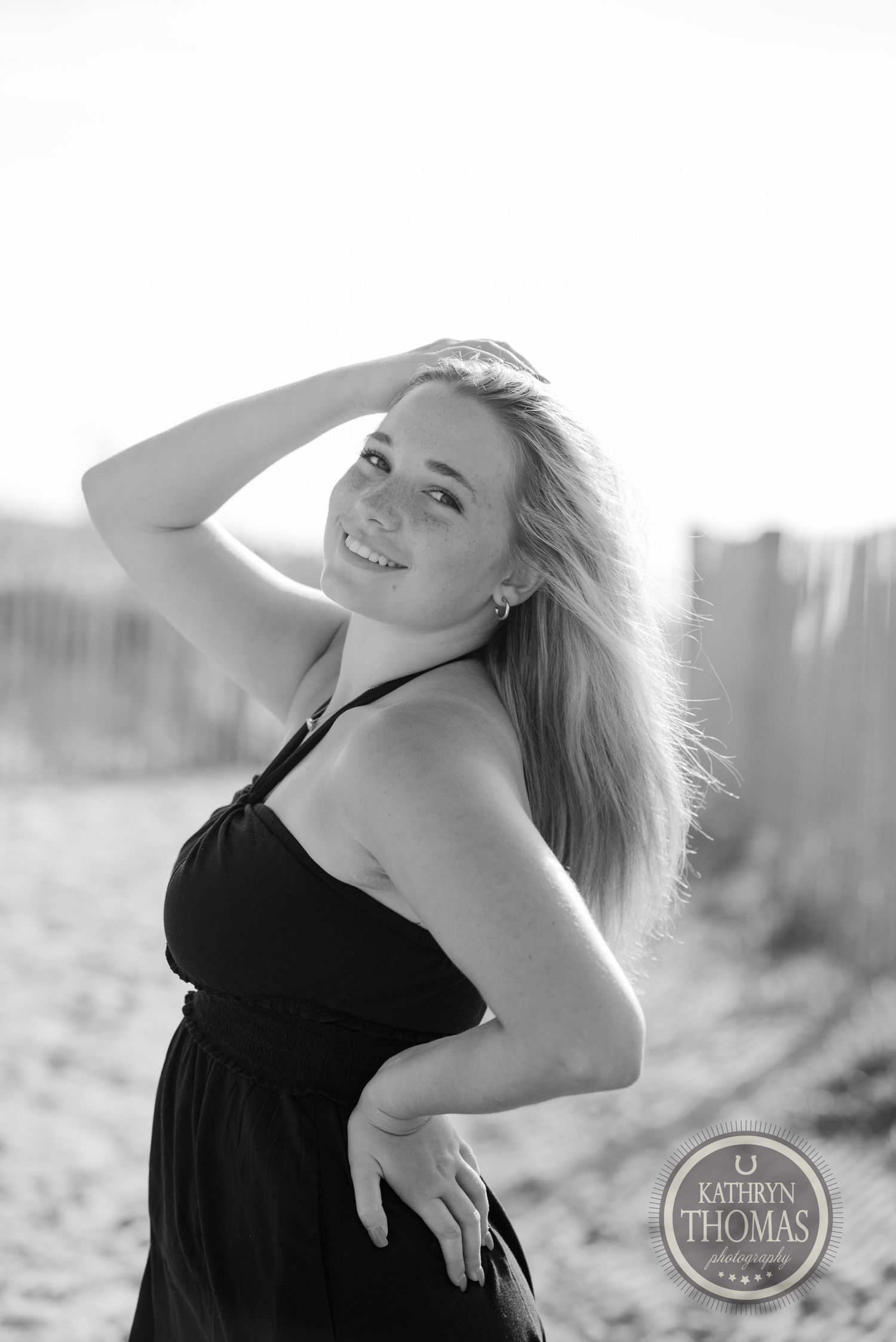 Black and white portrait at beach with sand fence in background.