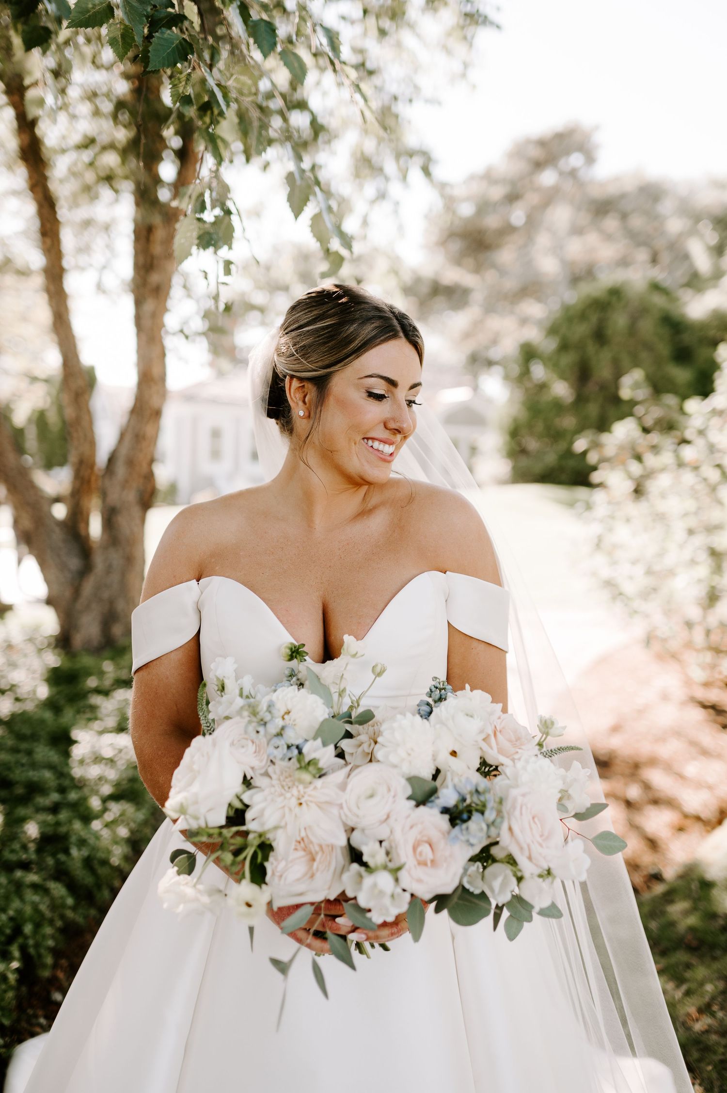 A stunning bridal bouquet of white and blush roses against a soft outdoor background.