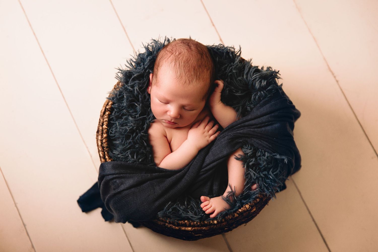 newborn photo session baby in basket with blue fur and wrap