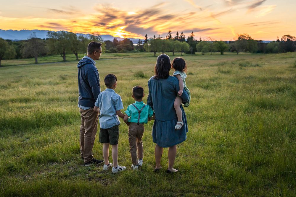 Seattle family photographer capturing family holding hands and looking at sunset
