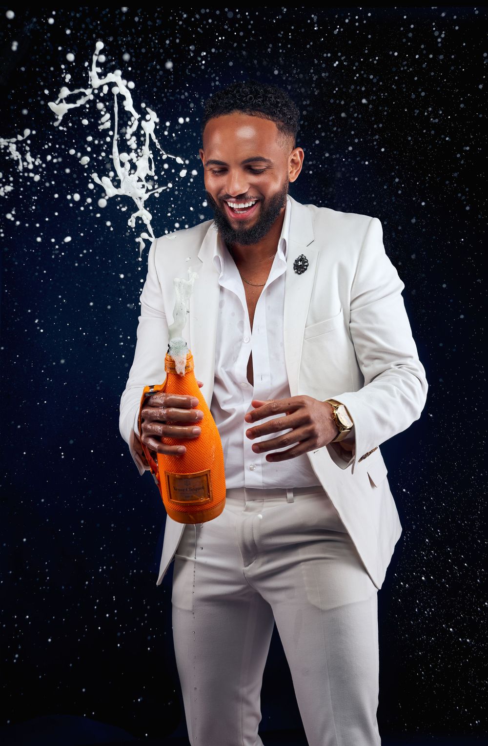 Person in white suit splashing orange beverage bottle against starry night background.