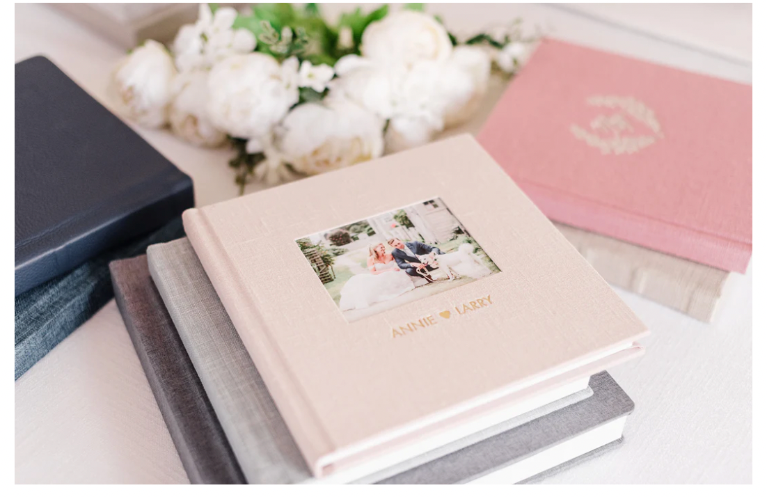 Wedding photo albums in cream and pink with white flowers.