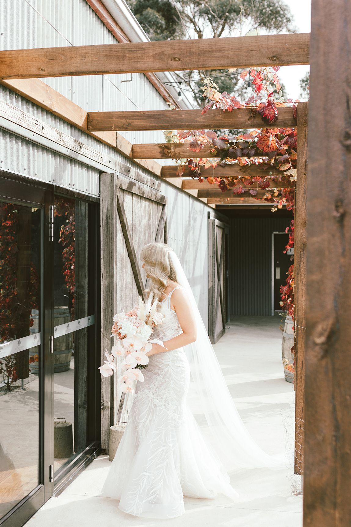 Rustic outdoor walkway with wooden beams and climbing pink flowers.