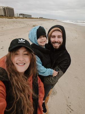 Group taking selfies and having fun on a cloudy beach.