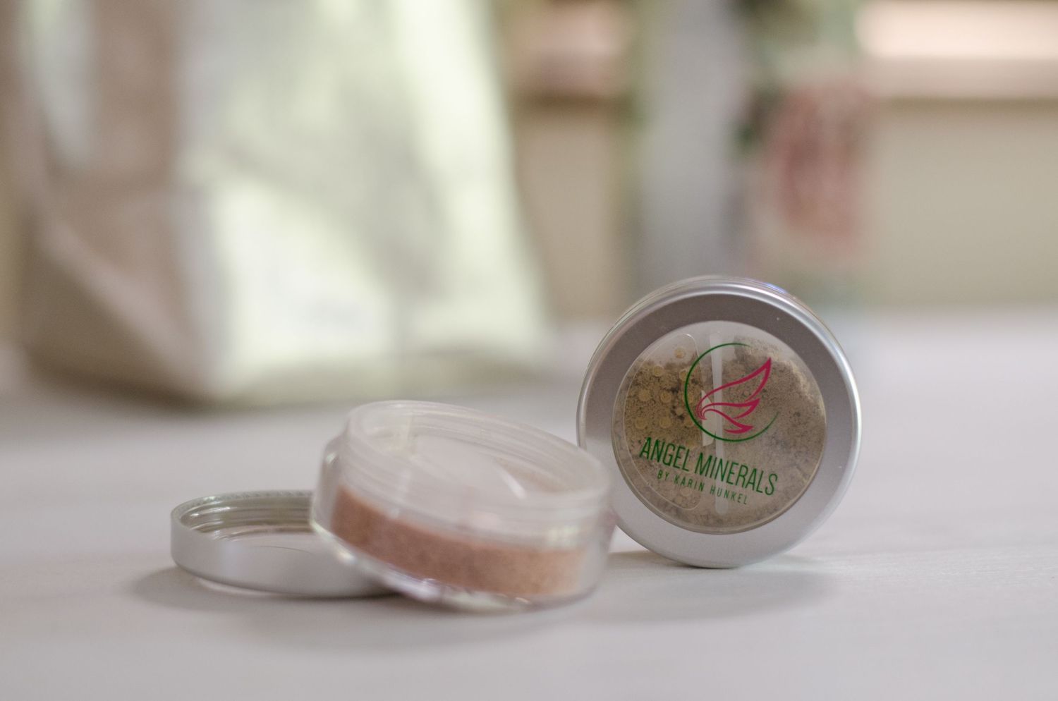 Elegant cosmetic jars with pink floral designs arranged on white surface.
