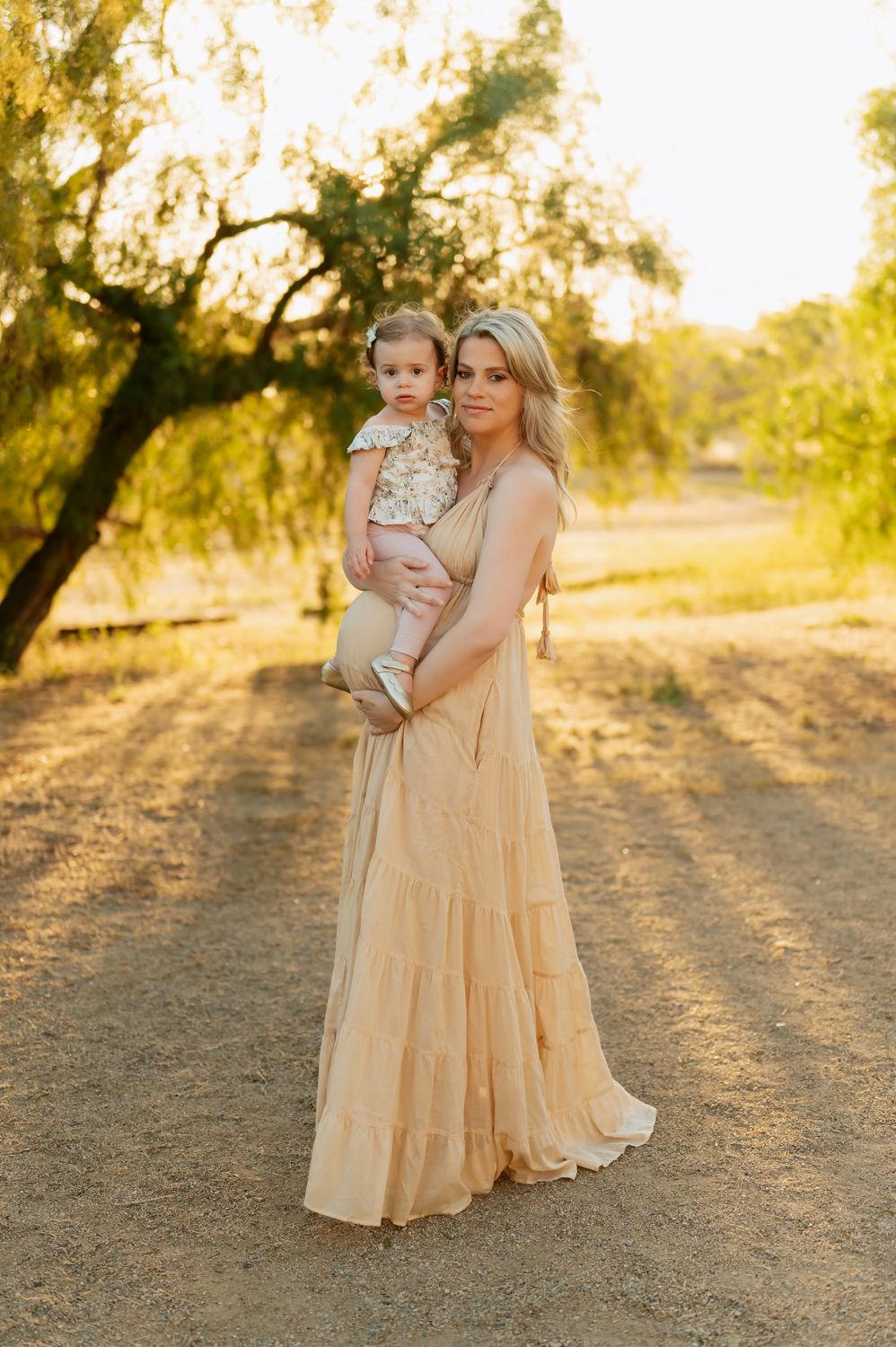 mom holding toddler girl on pregnant belly during family photoshoot by San Diego photographer, Tiffany Kelterer