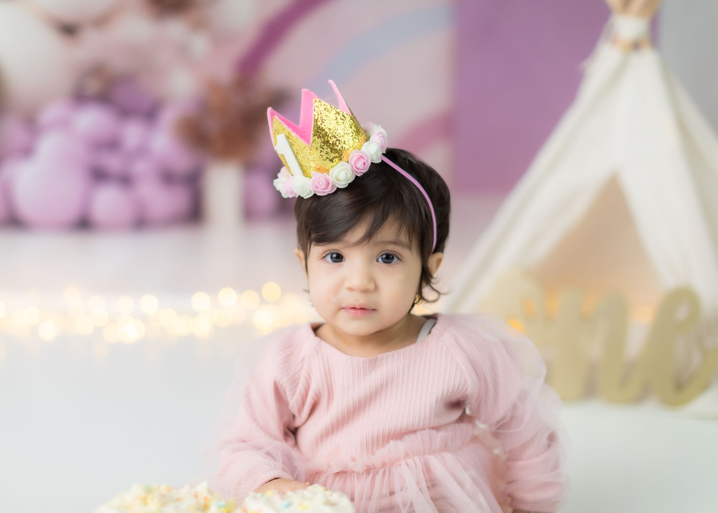 Birthday celebration scene with pink dress and white teepee against pastel decorations.