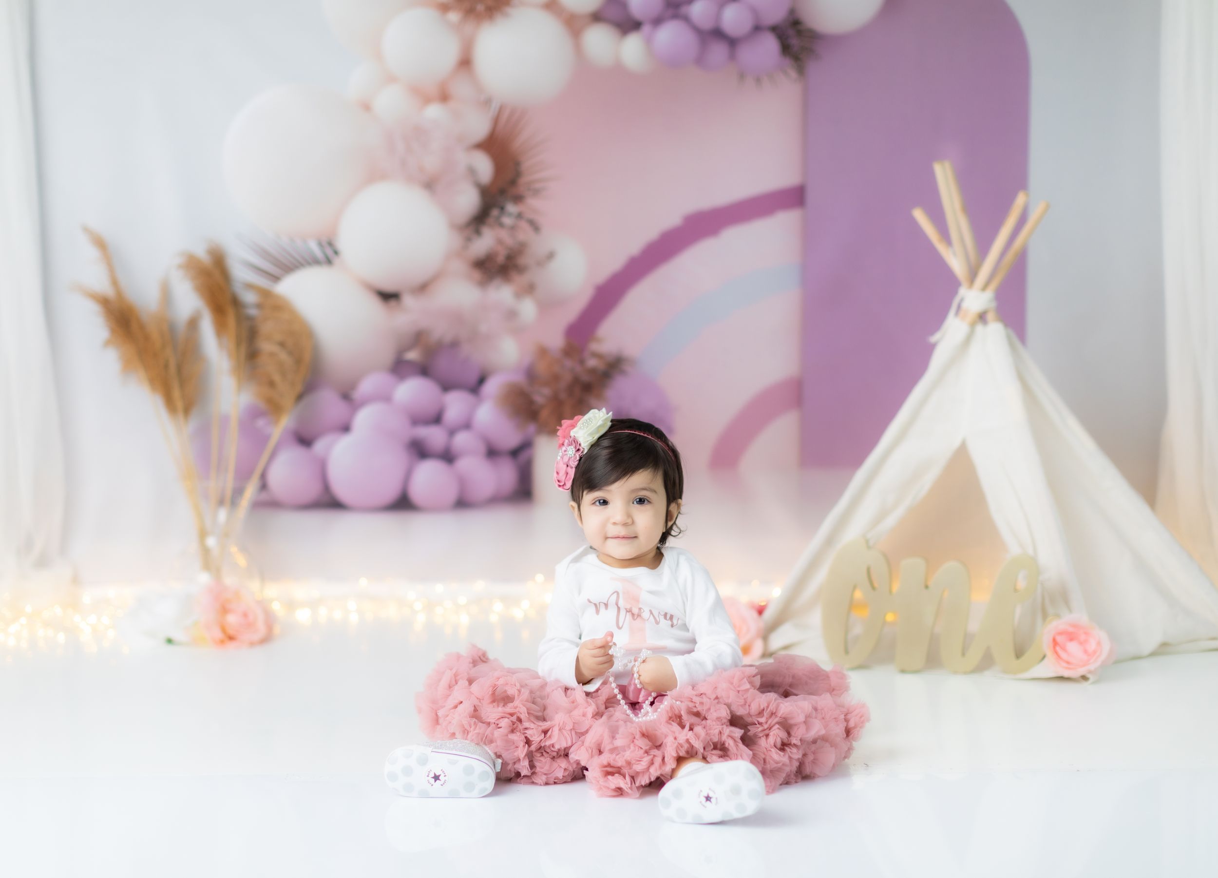 Dreamy pink and purple balloon arch with teepee setup for children's photography.