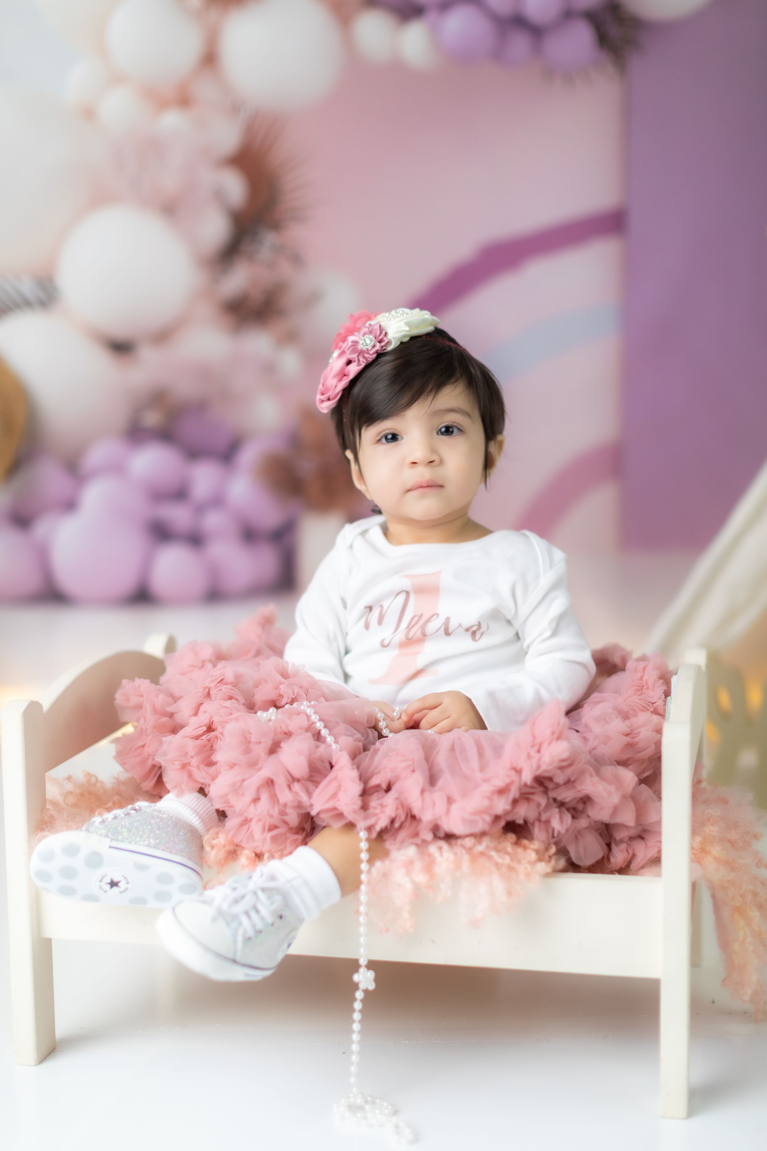 Pink and purple themed children's photography setup with balloons and teepee.