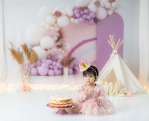 Ethereal birthday photo setup with balloon arch and white teepee decorations.