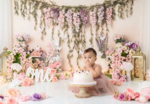 Floral backdrop with pink roses and hanging greenery set up for baby photography session.